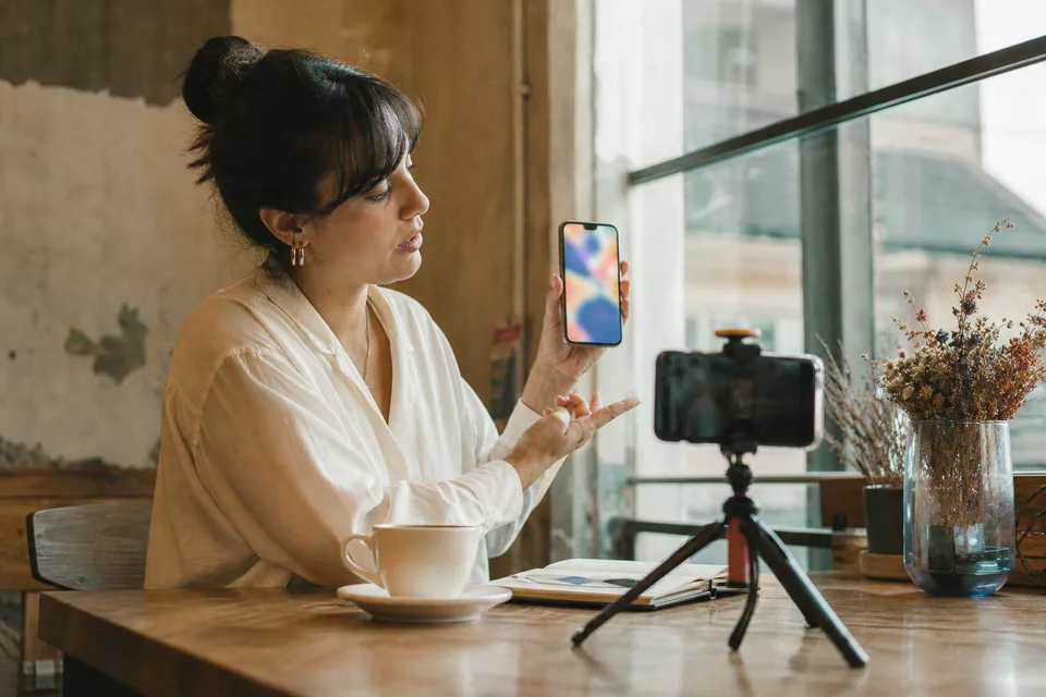 A creator smiles at the camera while holding a phone